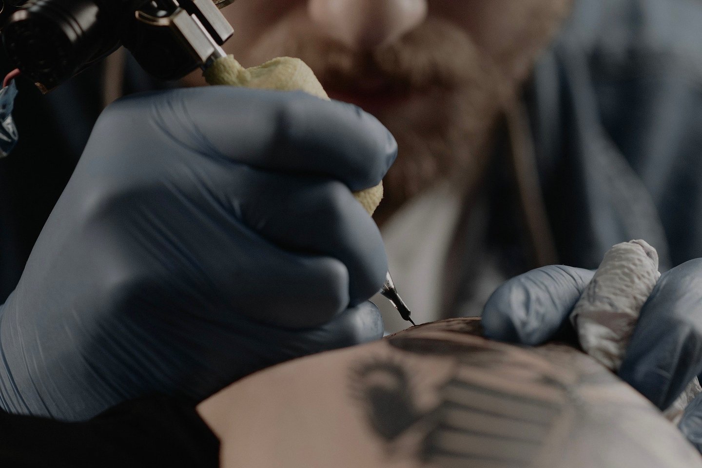 Тату-мастер наносит тату в салоне