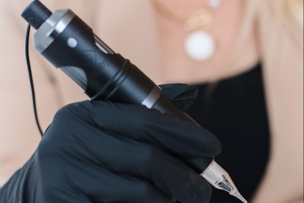 Тату-майстер з машинкою в рукавичках